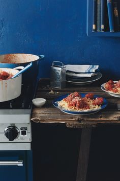 two plates of food sit on a table in front of a blue wall and stove