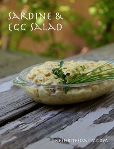 a glass bowl filled with food sitting on top of a wooden table next to a plant