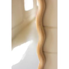 a curved wooden mirror hanging on the wall