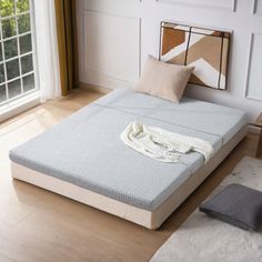 a bed sitting on top of a hard wood floor next to a window and door