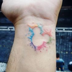 a person with a colorful tattoo on their wrist that has the shape of a heart