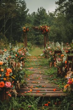 an outdoor wedding ceremony with flowers on the aisle and wooden benches lined up along the path