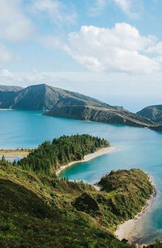 an island in the middle of a lake surrounded by hills and trees on both sides