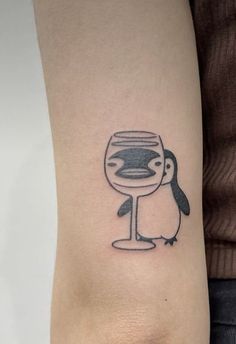 a penguin with a wine glass tattoo on its arm