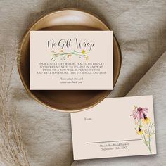 an envelope and business card sitting on top of a plate next to some dried flowers