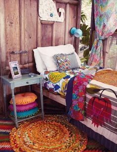 a bed with colorful blankets and pillows on top of it next to a small table