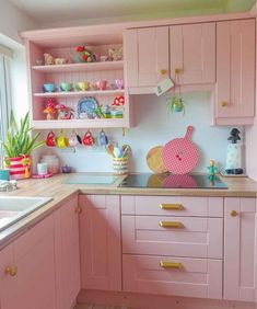 a kitchen with pink cabinets and gold pulls on the cupboards is pictured in this image