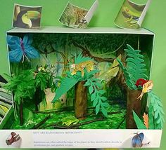 an open box with paper cut out of animals and plants in the forest on it