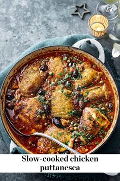 a pot filled with chicken and vegetables on top of a blue towel next to wine glasses