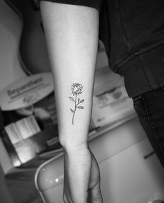 a woman's arm with a single rose tattoo on the left inner forearm and wrist