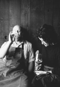 two people sitting next to each other in front of a wooden wall