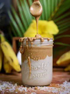 a spoon is pouring peanut butter into a jar