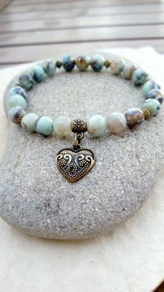 A gentle energy emanates from this "Connection" bracelet in aqua terra jasper. It will help you keep a positive state of mind, regain hope if you no longer have any, it will bring you peace, harmony and a feeling of compassion for others and for yourself. Composed of 21 aqua terra jasper beads, decorated with small bronze-colored metal beads and a pretty heart-shaped "love" medal. Dimensions: approximately 18 cm (can be adjusted on request, other sizes possible on order) Because you are unique, Earthy Amazonite Jewelry For Gifts, Earthy Amazonite Jewelry Gift, Spiritual Jasper Beaded Bracelets As Gift, Bronze Bracelets With Natural Stones For Gift, Releasing Negative Energy, Pretty Heart, Aqua Terra, Jasper Beads, State Of Mind