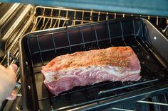 an open oven with meat cooking in it and someone pulling something out of the oven