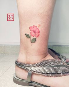 a woman's foot with a pink flower tattoo on the side of her leg