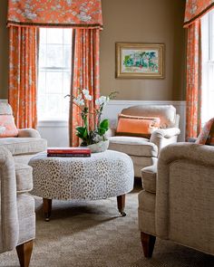 a living room with leopard print furniture and orange drapes on the windowsills