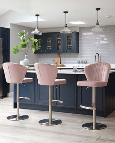 two pink chairs sitting in front of a kitchen island with blue cabinets and counter tops