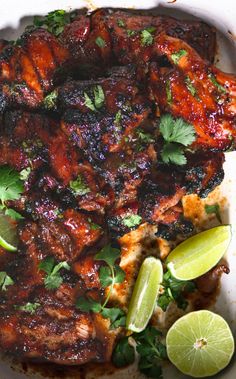 grilled chicken with limes and cilantro garnish on a white plate