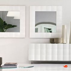 two mirrors are hanging on the wall above a coffee table and sideboard in a modern living room