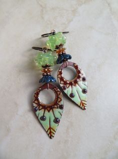 two pairs of earrings with green and brown beads hanging from them on a marble surface