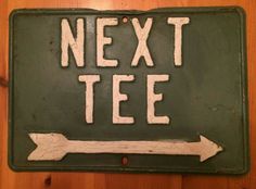 a sign that says next tee with an arrow pointing to the right on a wooden surface