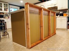 a kitchen with an island made out of wood and glass doors on the back wall