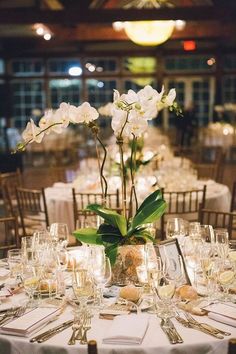 a table set up with white flowers and place settings for an elegant dinner or reception