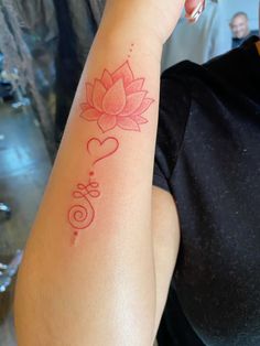 a woman with a tattoo on her arm that has a pink flower in the shape of a heart