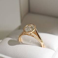 a yellow gold ring with a white diamond in it's center sits inside a box