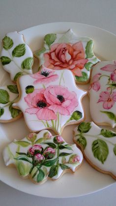 several decorated cookies on a plate with flowers and leaves painted on the outside of them