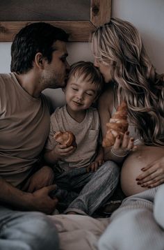 a man, woman and child sitting on a bed with food in their hands as they look at each other