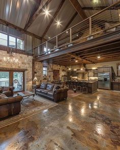 a large open living room with high ceilings and exposed wood beams on the ceiling is furnished with leather couches