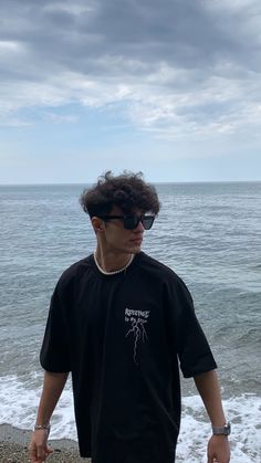 a man standing on top of a beach next to the ocean