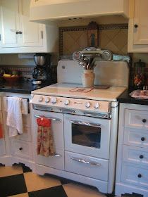 a white stove top oven sitting inside of a kitchen next to a black and white checkered floor