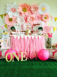 a table with pink and white decorations on top of green carpeted floor next to wall