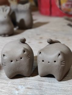 two clay cats sitting on top of a wooden table