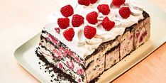 a chocolate cake topped with raspberries on top of a white table next to a cup