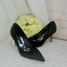 a pair of black high heeled shoes next to a bouquet of white roses