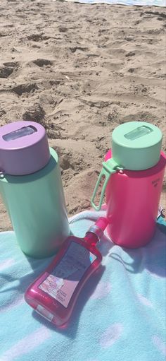 two cups and a cell phone on a towel at the beach