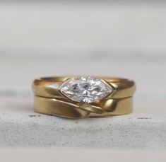 two gold wedding bands with a diamond in the center, on top of each other