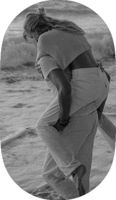 a black and white photo of a woman on the beach with her back to the camera