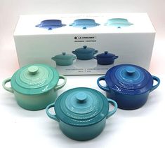 three blue pots and one green pot are in front of a box with the lid open