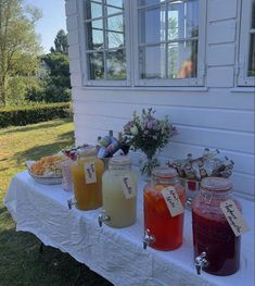 there are many jars on the table with drinks in them, and some flowers behind it