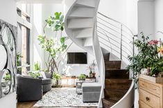 a living room filled with lots of furniture next to a spiral stair case in front of a window