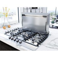 a stove top oven sitting on top of a counter next to a vase with flowers