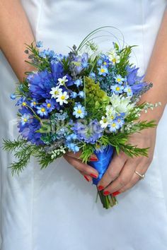 a bride holding a bouquet of blue and white flowers