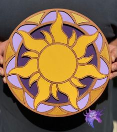 a person holding up a purple and yellow plate with an image of the sun on it