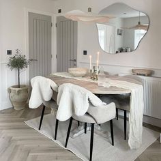 a dining room table with two chairs and a mirror