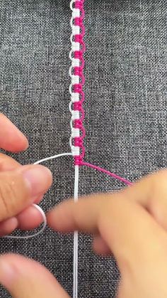 someone is stitching the end of a piece of fabric with pink and white thread