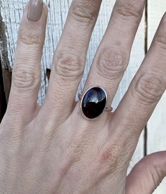 This dark red large oval garnet has been set in sterling silver with a handmade ring band from sterling silver half dome wire. These garnets are a dark blood red with a bright red that emerges when the light catches the stone. Each stone is 18mm x 13mm in size. The stone can be set horizontally (east/west) or vertically (north/south). Made to order! Choose your size! The root of red garnet stone meaning is all about regeneration and energizing. Garnet meaning also includes balancing, protecting Adjustable Oval Ruby Ring, Oval Cabochon Ruby Ring In Sterling Silver, Sterling Silver Ruby Ring With Polished Finish, Sterling Silver Oval Cabochon Ruby Ring Gift, Handmade Oval Garnet Rings, Oval Ruby Ring With Polished Finish In Sterling Silver, Handmade Oval Ruby Ring In Sterling Silver, Handmade Oval Garnet Jewelry, Garnet Stone Meaning